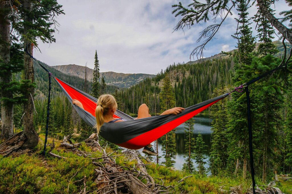 woman in hammock in green mountains by lake