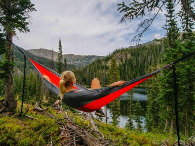 woman in hammock in green mountains by lake